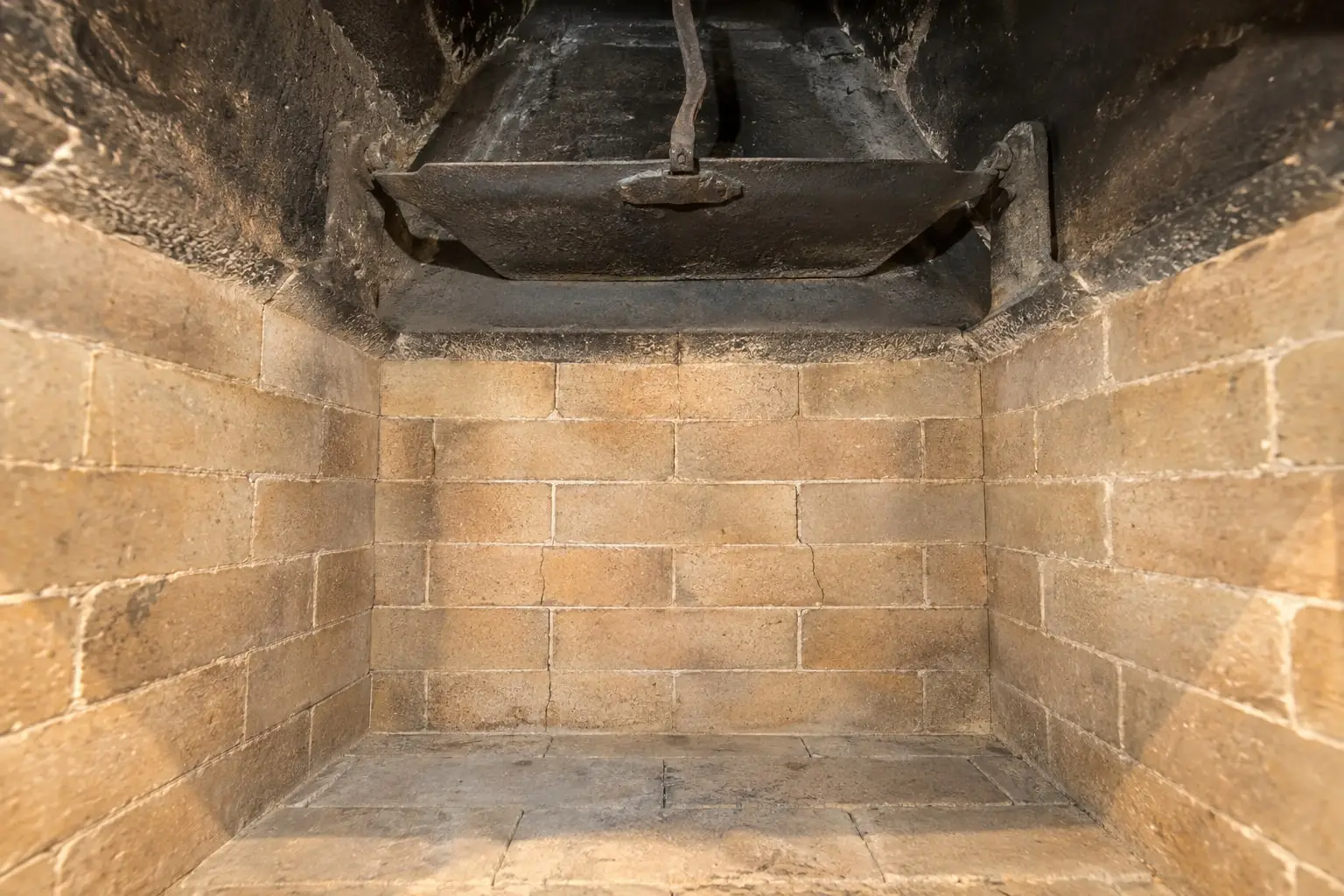 Inside a swept fireplace firebox lit by a work light, the open damper visible above